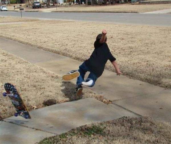 A person falling of their skateboard onto the sidewalk