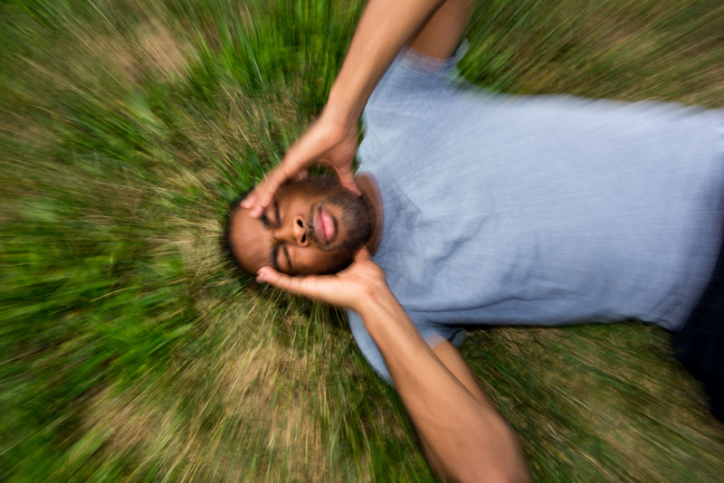 concussion symptoms - man laying on grass holding his head with both hands
