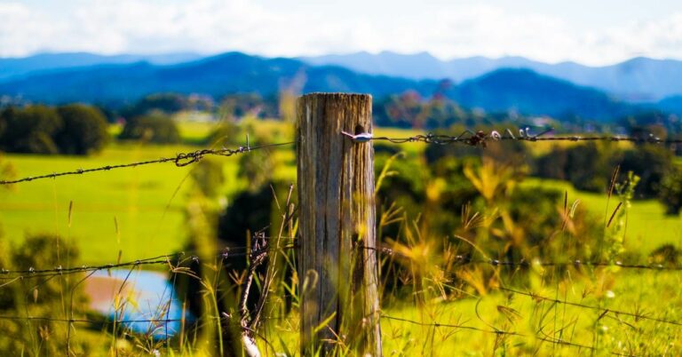 wood post with wire fencing with mountains in the background - like on a ranch